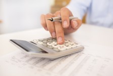 A close-up of a man doing accounting work on a calculator